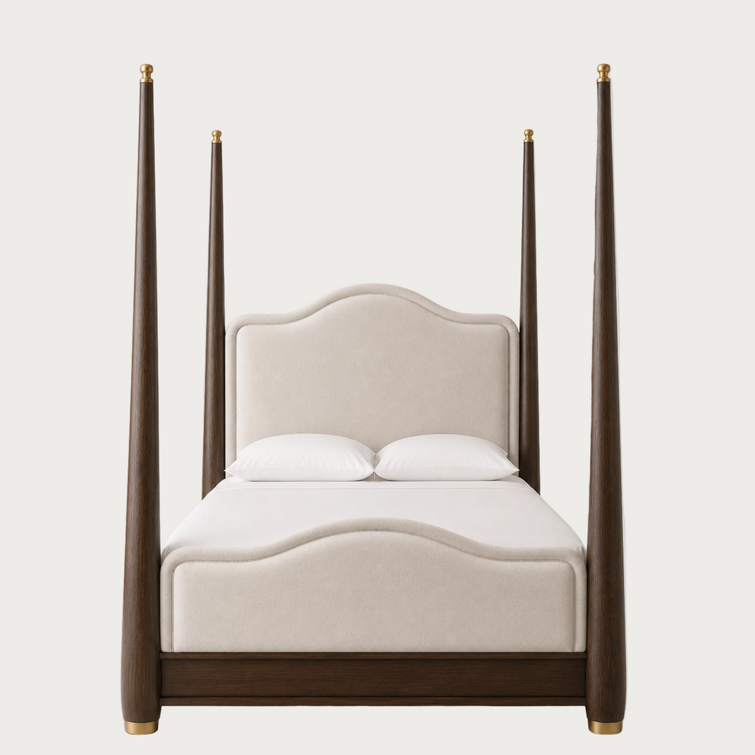 A modern four-poster bed featuring a dark brown wood frame with gold-toned metal caps on the posts and footboard, paired with a cream upholstered headboard and white bedding, shown against a solid light gray background.