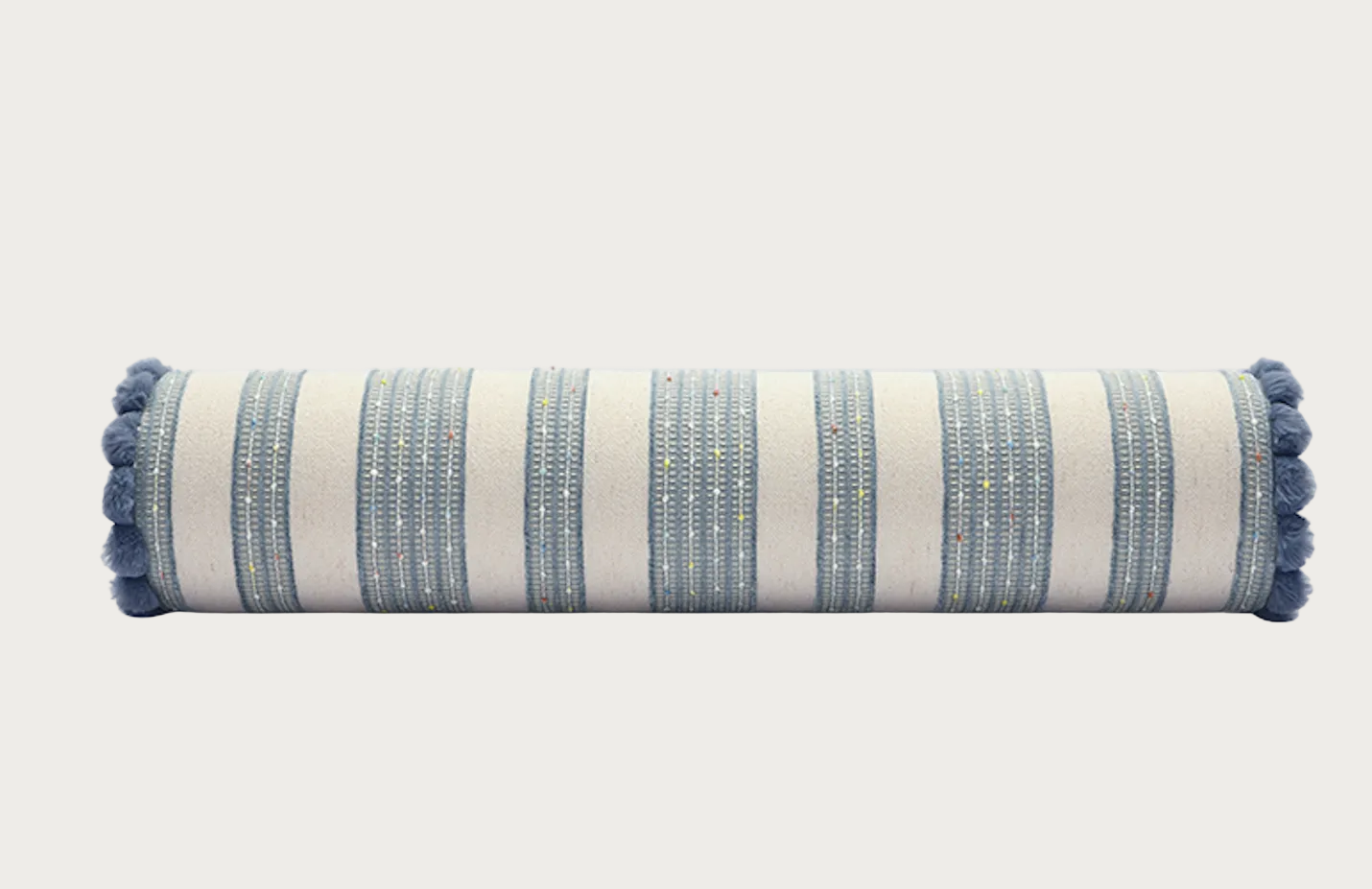 A cylindrical bolster pillow with a cream and blue striped pattern and blue pom-pom trim on both ends, shown against a light gray background.