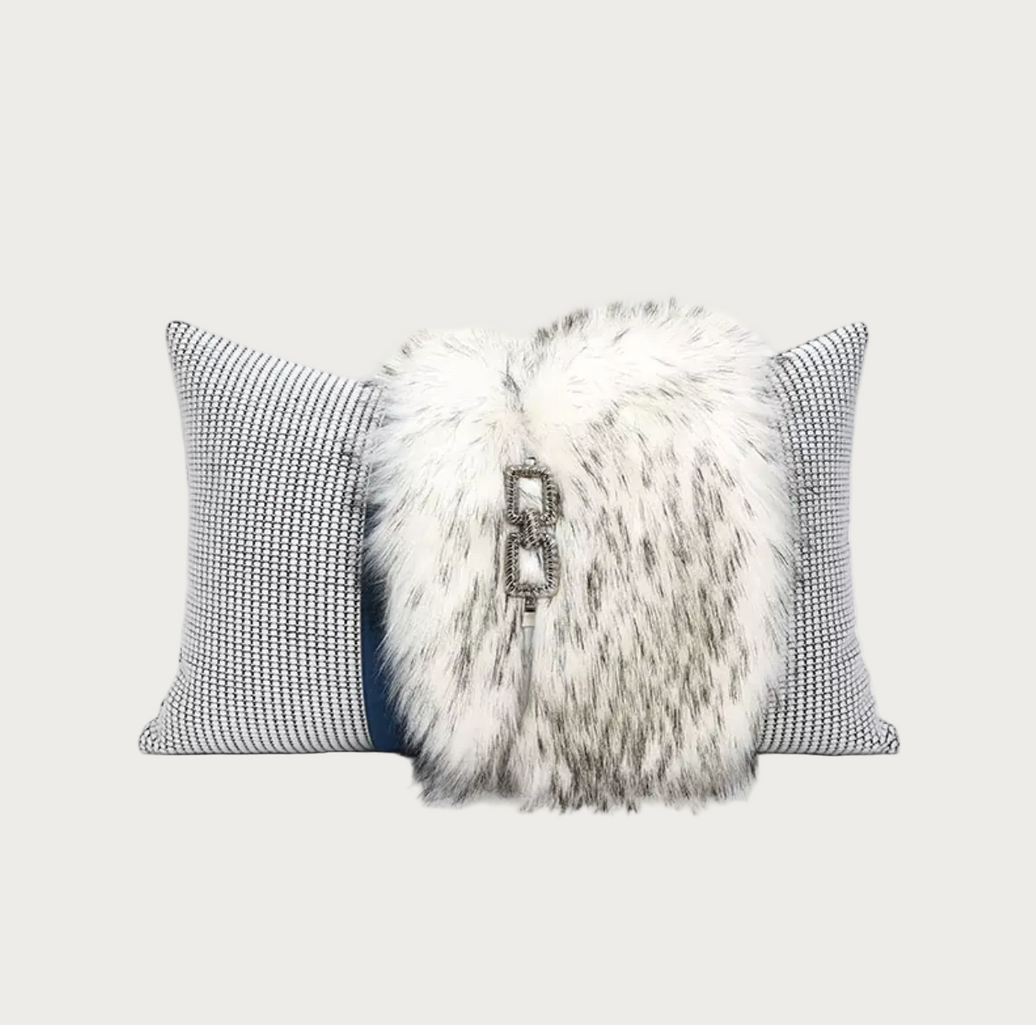 A decorative throw pillow set featuring a central white and gray faux fur pillow with a silver-tone metal clasp, flanked by two gray and white patterned pillows on a white background.
