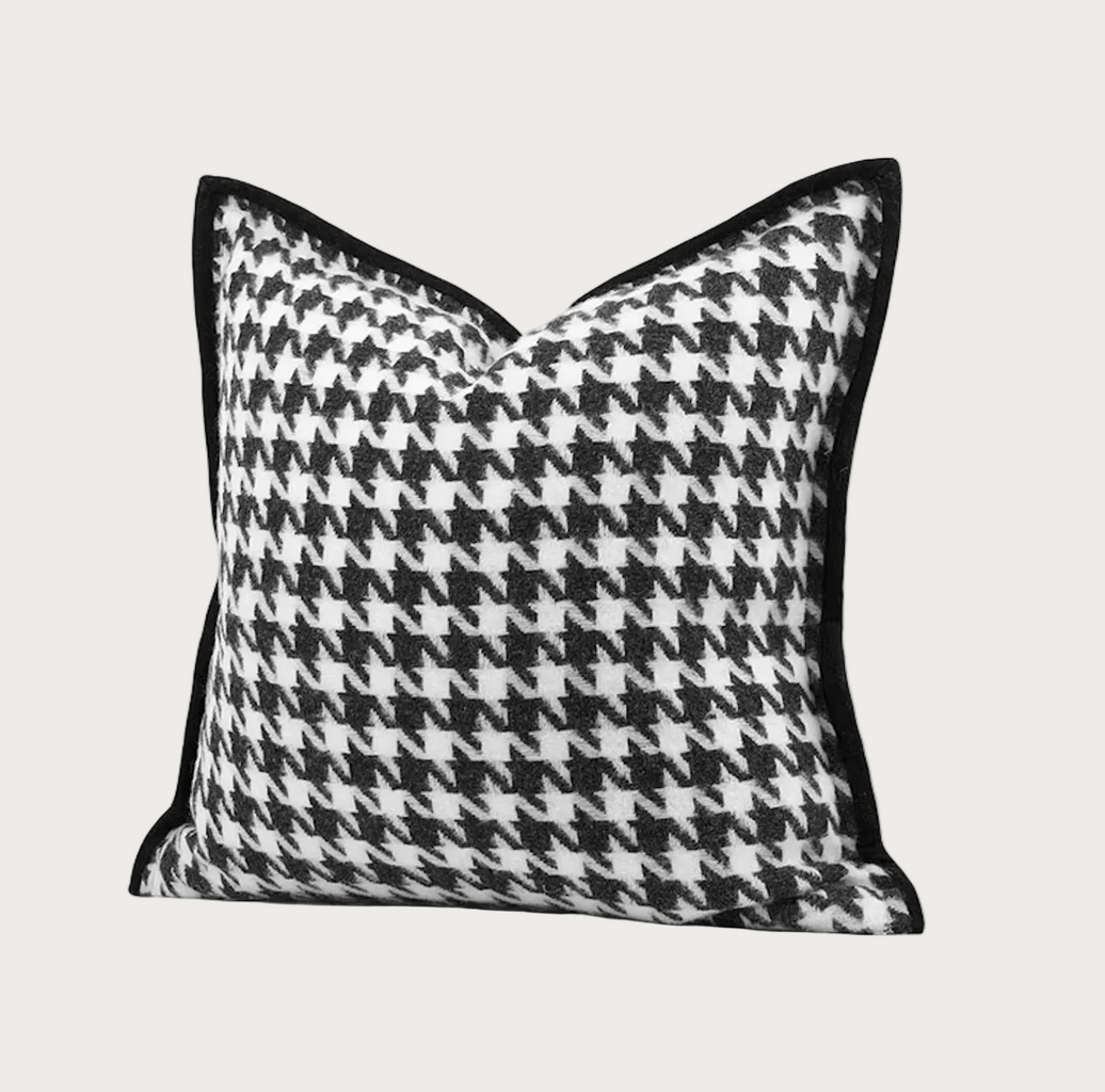 A square throw pillow featuring a black and white houndstooth pattern with solid black piped edges, shown against a plain white background.