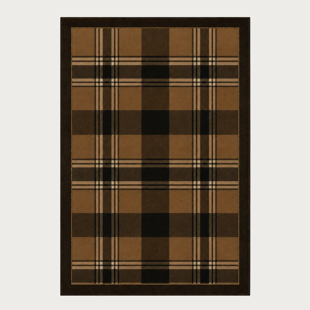 A rectangular area rug with a classic plaid pattern in shades of brown, tan, black, and beige, finished with a solid dark brown border, shown against a neutral light gray background.