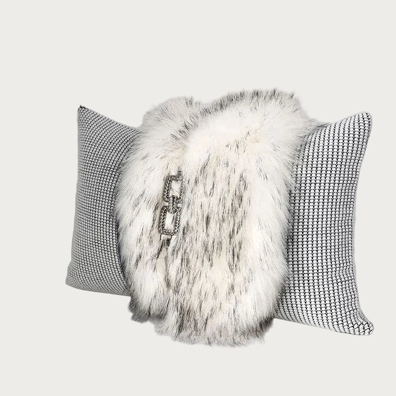 A decorative throw pillow set featuring a central fluffy white faux fur pillow with a silver-tone chain detail, flanked by two square pillows with a black and white houndstooth pattern, set against a neutral gray background.