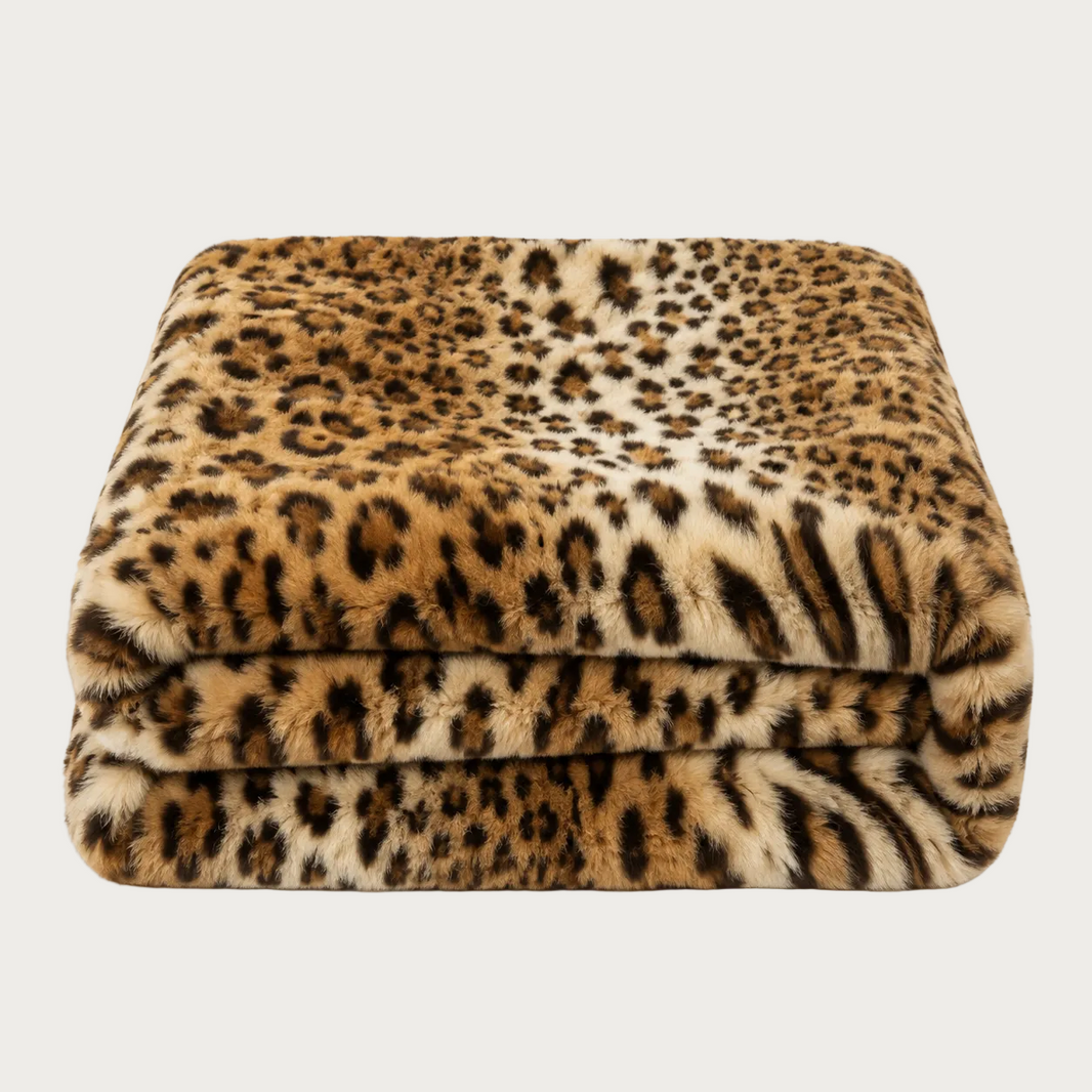 A folded plush throw blanket featuring a leopard print pattern in shades of brown, beige, and black, set against a plain white background.