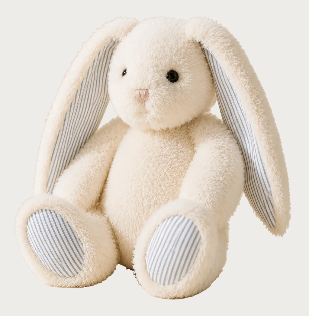 A plush cream-colored bunny toy with long floppy ears and blue-and-white striped inner ears and paw pads, photographed on a warm beige studio background.