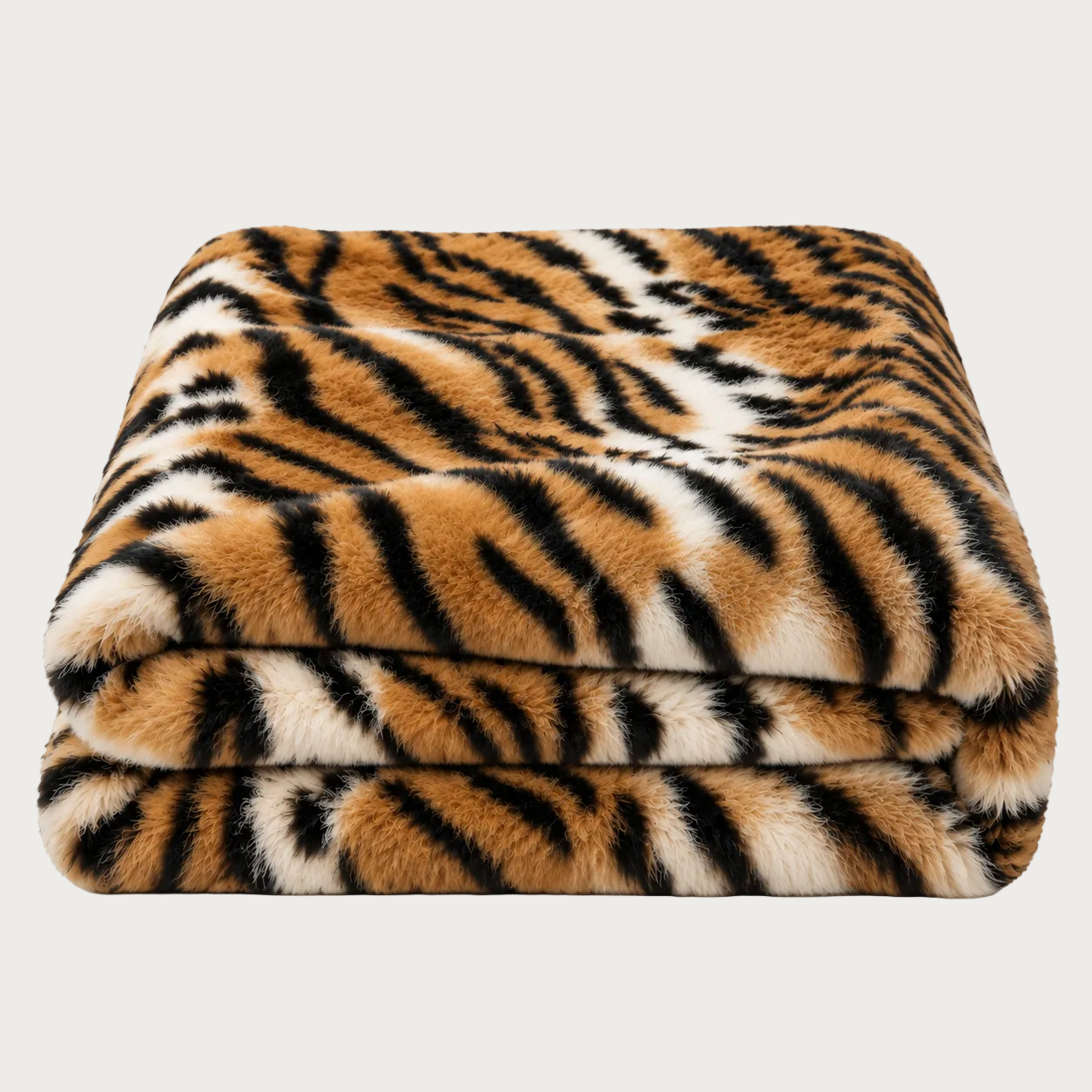 A folded plush faux-fur blanket with a tiger stripe pattern in orange, black, and cream, shown on a clean white background.